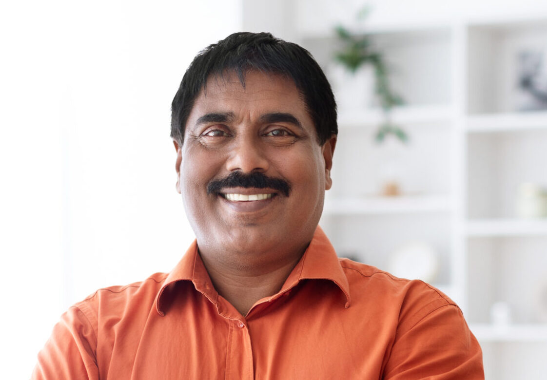 handsome cheerful mature indian man posing at home office
