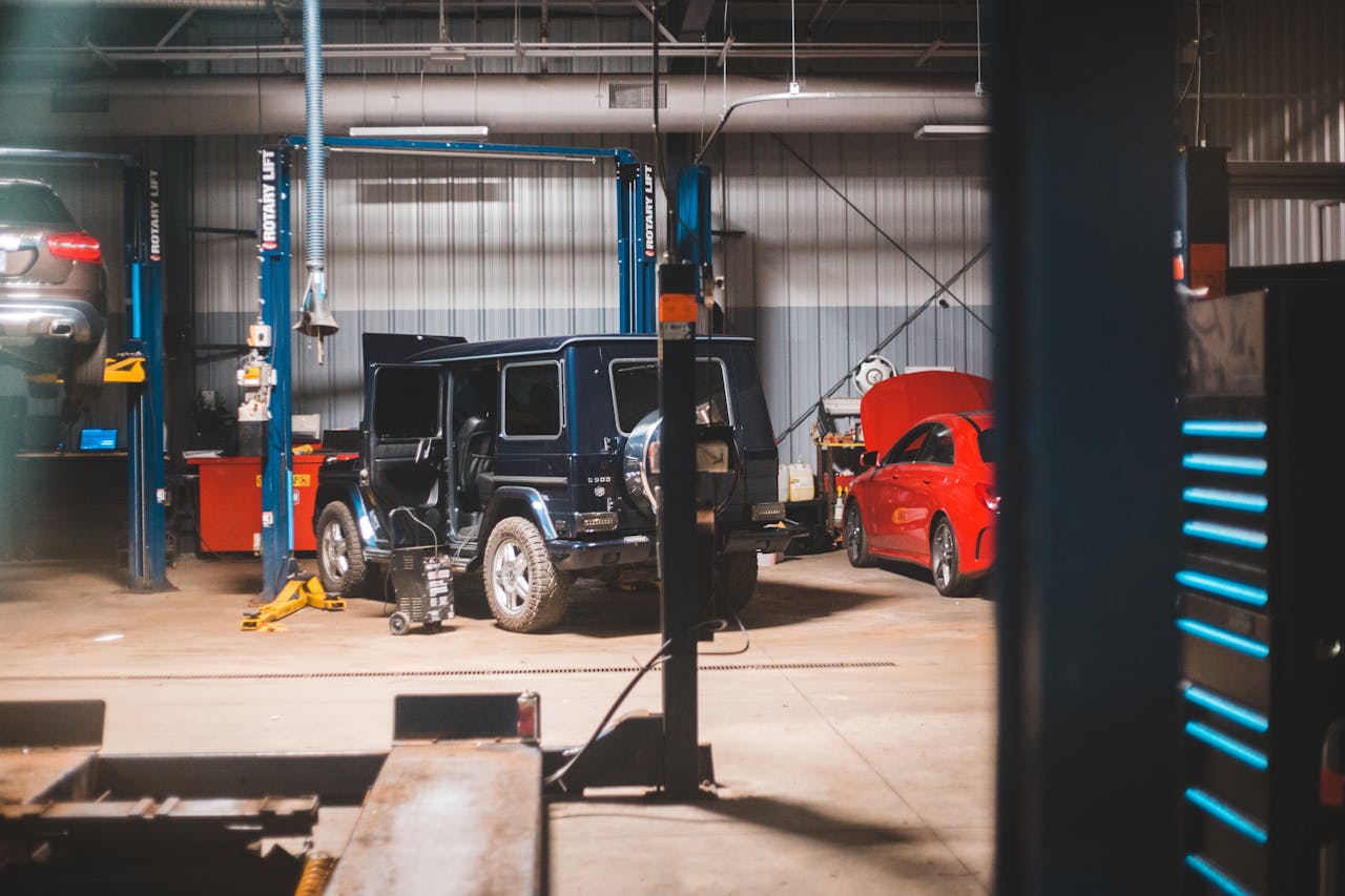 Interior view of a spacious garage with cars undergoing repair work under bright lights.